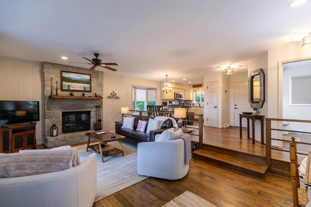 A welcoming living area featuring a cozy fireplace, comfortable sofa, spacious dining area, and wooden staircase. The space is arranged to foster social gatherings, relaxation, and shared experiences like movie nights or game evenings.