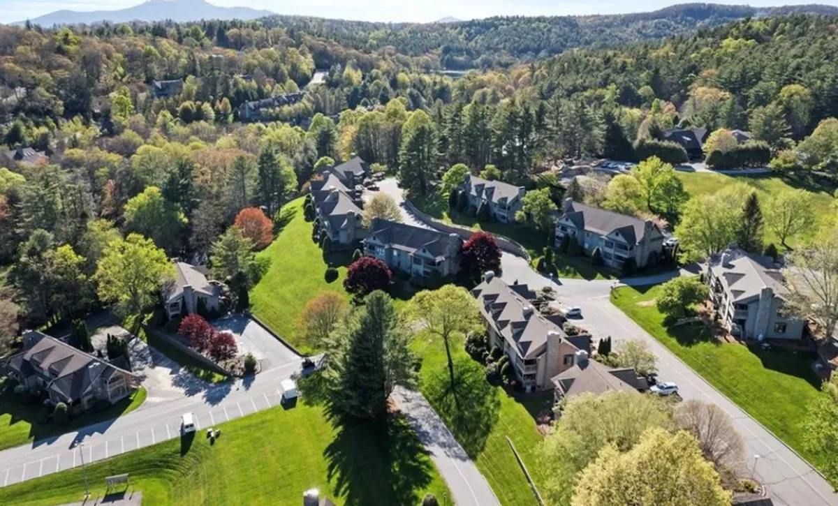 An exterior view showing lush greenery, residential buildings, winding roads, and colorful trees, evoking the resort’s landscaped grounds and community setting. The scene is vibrant, peaceful, and inviting, ideal for walking and exploring.