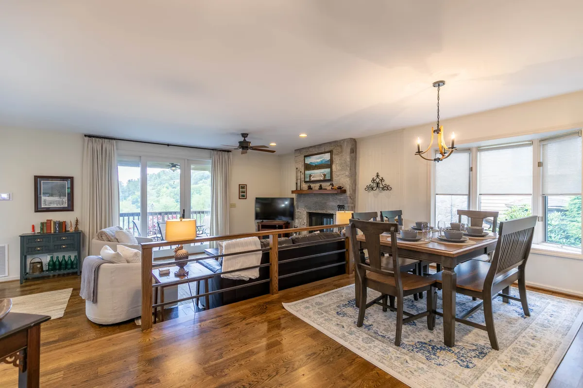 A welcoming dining area featuring a dining table set near a fireplace and large windows that offer a glimpse of the outdoors. The space exudes warmth, making it ideal for family dinners, social gatherings, or enjoying coffee while taking in natural views.