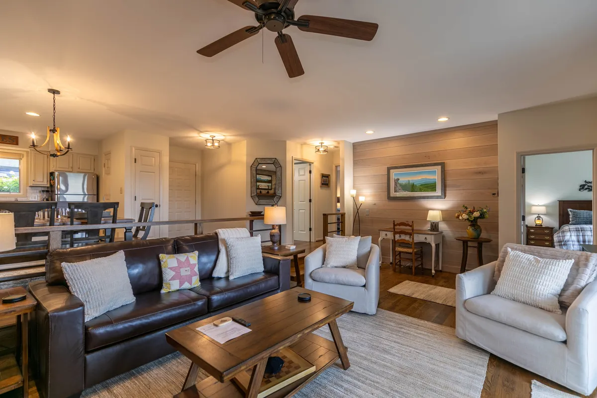 A thoughtfully styled living area with a plush sofa adorned with decorative pillows, a wooden coffee table perfect for casual chats, and tasteful artwork brightening the walls. Natural light and stylish touches create a comfortable, welcoming setting.